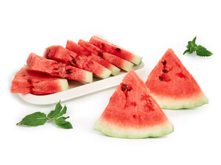 Sliced pieces of ripe, red watermelon on a white plate with mint leaves