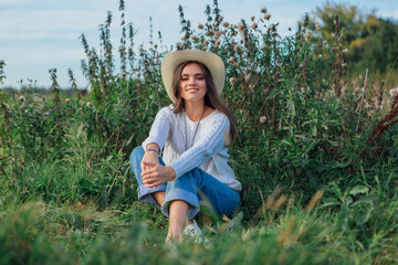 Beautiful brunette teenage girl sitting on the grass and smiling