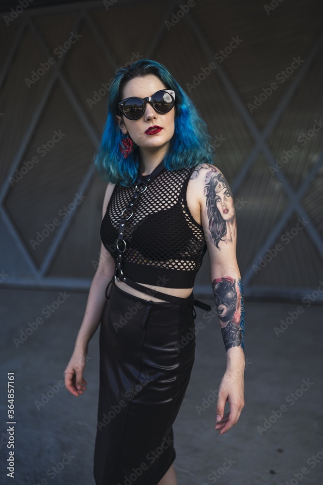 Sticker European female with tattoo and blue hair wearing sunglasses and sexy black dress posing