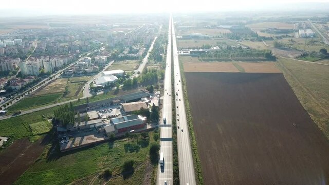 aerial view of double lane intercity road. wheat fields and buildings can be seen