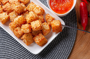 .Squares of tapioca and cheese served with pepper jelly. Wooden table. Space for text - Dice of tapioca. Top view