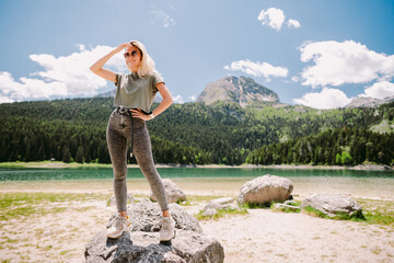 Naklejka premium attractive woman relax in mountains with lake view. Joyful female solo traveller travel with lake and forest view in summer day. Montenegro, The black lake. 