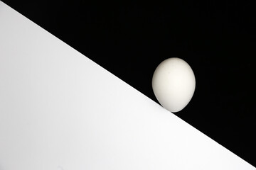Single white egg balanced on lower right of diagonal black and white background