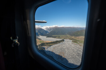 The view out the window of a scenic flight looking out to river formations and the mountains in New Zealand