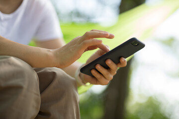 Relaxing in hammock hand using smartphone in tropical forest