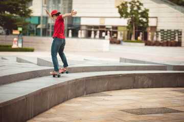 Asian woman skateboarder wearing facemask skateboarding in modern city