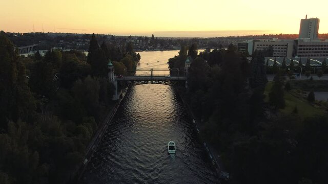 City Waterway Aerial Following Boat to Historic Bridge with Cars Commuting at Sunset