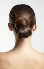 Back view portrait of beautiful young dark brunette woman on gray background.