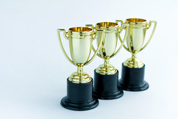 Three golden winner cups on a white background. Competitions concept.