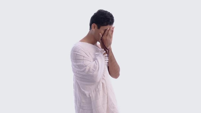 Muslim man praying wearing ihram isolated over white background