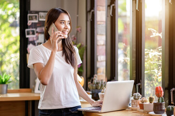 Asian woman or a happy student smiles on a desk with a computer.