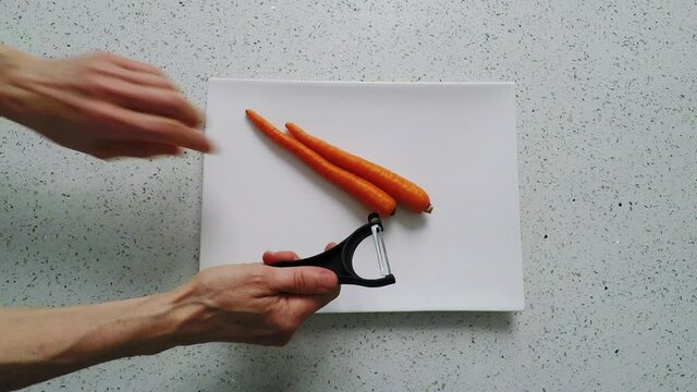 Carrot sticks are peeled on white plate, as peanut butter is added to make a snack. HD, bird's eye view, studio lighting in kitchen.
