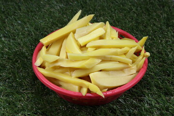 Pile of slices pickled bamboo shoot in the plastic basket on the grass field. Famous fresh vegetable ingredients in local Thailand. Sour taste. 