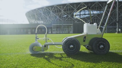 Side view of Marking football stadium field using a professional paint machine