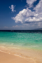 Fototapeta na wymiar Karibischer Strand mit türkisfarbenen Wasser und bewölktem Himmel