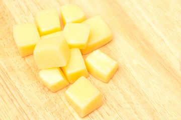 Close Up of Mozzarella Cheese Cubes on Wooden Plate Isolated on White Background