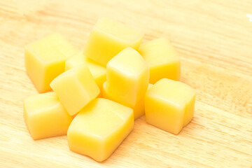 Close Up of Mozzarella Cheese Cubes on Wooden Plate Isolated on White Background