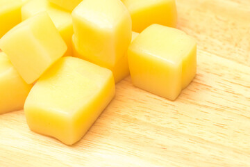 Close Up of Mozzarella Cheese Cubes on Wooden Plate Isolated on White Background