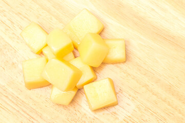 Close Up of Mozzarella Cheese Cubes on Wooden Plate Isolated on White Background