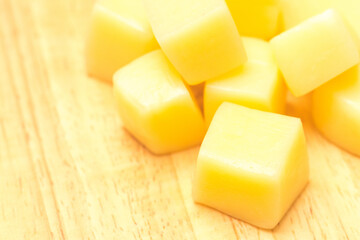 Close Up of Mozzarella Cheese Cubes on Wooden Plate Isolated on White Background