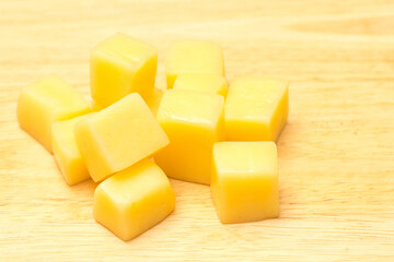 Close Up of Mozzarella Cheese Cubes on Wooden Plate Isolated on White Background