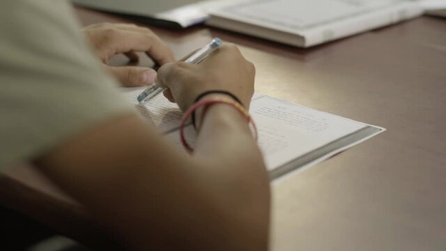 A student tries to answer a test, Close-Up on the hand,
The student plays with the pen,
Hebrew language test. Hebrew lebanglesson