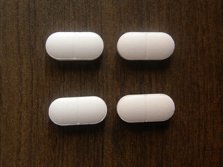 Small oblong shape white medicine tablets on wood background