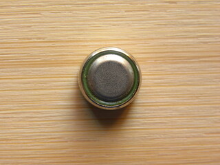 Small silver color button cell on wood background