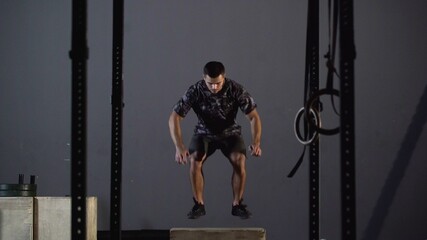 Fit Athletic Man Does Box Jumps in the Deserted Factory Gym. Intense Exercise is Part of Daily Cross Fitness Program.