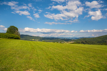 Countryside at high noon. Rural scenery with trees and fields on the rolling hills at the foot of the ridge.