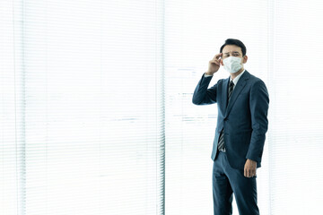 深刻そうに考えるマスクを着けた男性　感染症対策