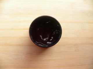 Black color round hair gel container kept on wooden table