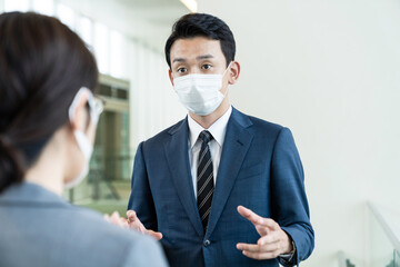マスクをして会話するビジネスマン　感染症対策　ソーシャルディスタンス