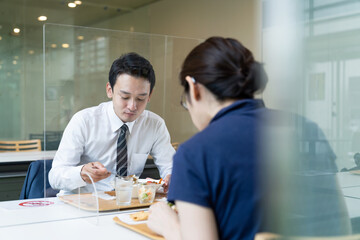 アクリルパーティションをはさんで食事する人々　飲食店の感染対策