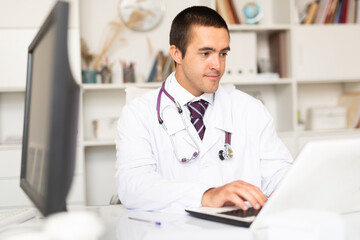 Cheerful man doctor working effectively in her office