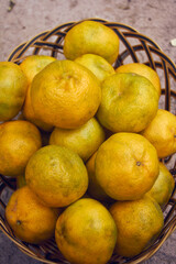 yellow ripe tangerines in a basket, green tones
