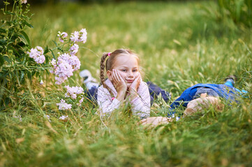 little girl sitting on the grass with a boy. Girl laughs while boy up his legs
