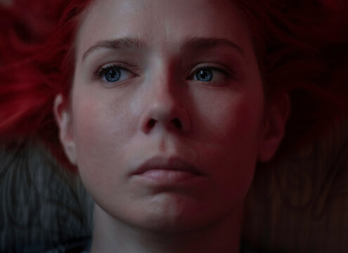 The red-haired girl lies and looks sadly away, only her face