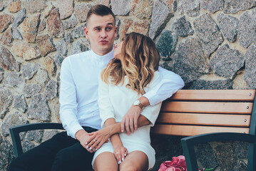 
The guy hugs a girl sitting on a bench