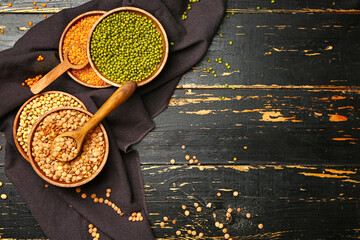 Different raw legumes on dark wooden background