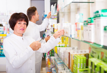 Friendly adult team of pharmaceutist and technician working in chemist shop