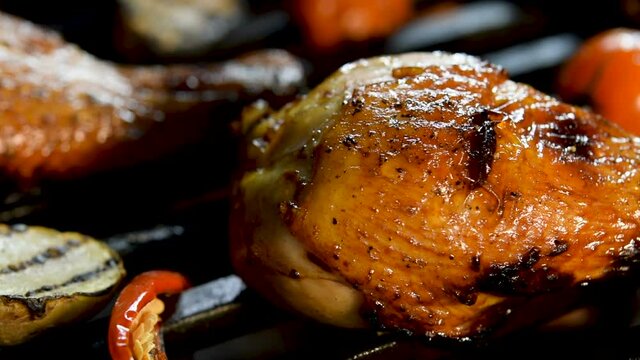 Close up grill roast bbq chicken leg with addition herbs and spices on the flaming grill.
