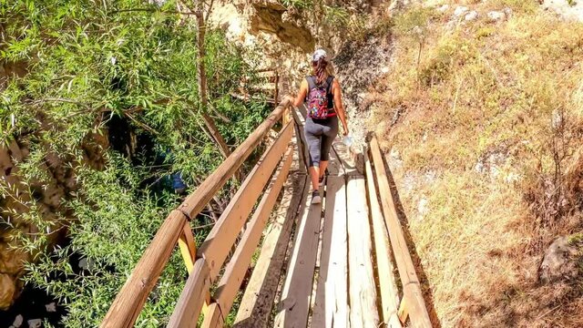 Castril, Sendero de la Cerrada, Spain, July 13, 2020: Woman walking carefully through 30 years old wooden path above Castril river. 