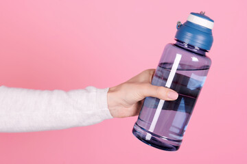 Hand with sport water bottle. Isolated on pink background.