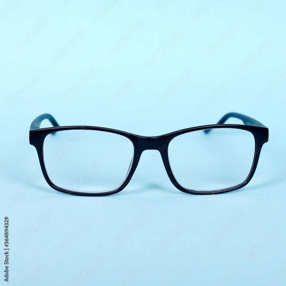 Wall mural Black classic eyeglasses, medicine contact goggless. Isolated on blue background.