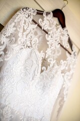 The bride's white dress hangs on a hanger

