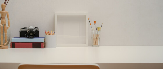 Copy space on study table with mock up frame, painting tools, camera, books on white desk