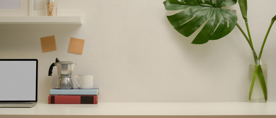 Modern workspace with copy space, mock up laptop, Mock pot, books and plant vase on white table