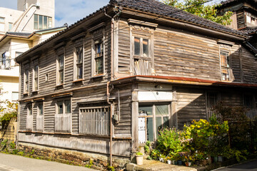 Fototapeta na wymiar Old, wooden abandoned house with plants in pots in front and broken windows in Kanazawa, Japan.