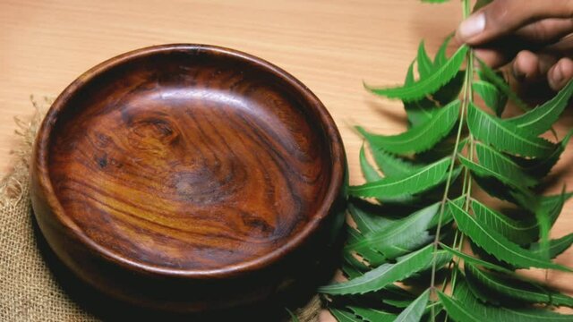 Neem fruit in wooden bowl with neem paste or juice,Mortar and pestle with medicinal neem leaves over wooden background, selective focus
